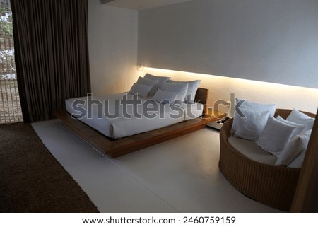 Interior photo of an empty living room bedroom from a resort hotel in Thailand Asia with a little sofa and white bed sheet sofa pillow white carpet floor night evening late time cosy comfortable