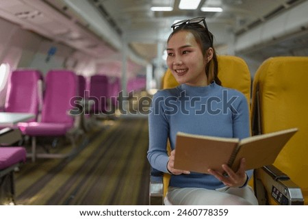 Asian female tourist sitting on a chair in the aisle holding a book travel journal Sit and read happily while traveling abroad. Travel concept business dealings.