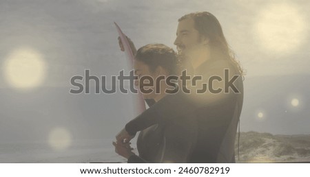 Image of spots over caucasian couple with surfboard. Free time, holidays and digital interface concept digitally generated image.