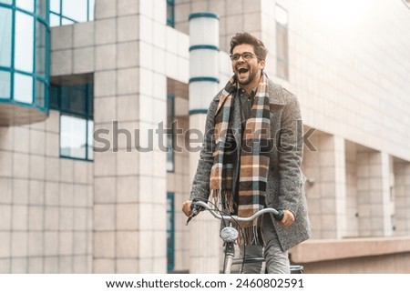Young cheerful businessman riding his bike to his work with a big smile on his face. Shot of a young businessman traveling through the city with his bicycle.