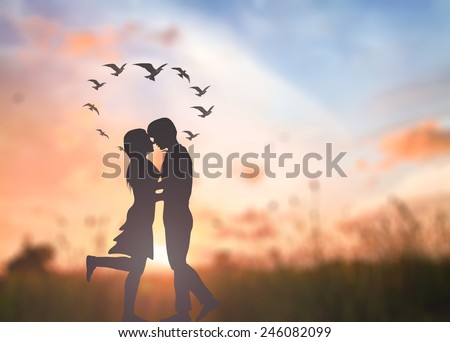 Silhouette couple over blurred sunset background.