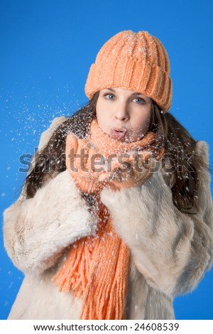 Picture of a beautiful brunette girl in the orange cap and coat on a blue background