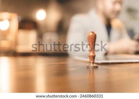A wood stamp with blur businessman. Concept of agreement, justice, approval and authority. Success business company complete. Insurance document approve signature or signing. Lawyer stamp guarantee Royalty-Free Stock Photo #2460860331