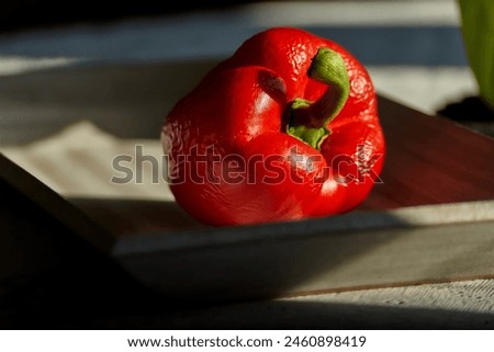 a shriveled but still edible bell pepper lies in the sunlight on a wooden plate Royalty-Free Stock Photo #2460898419