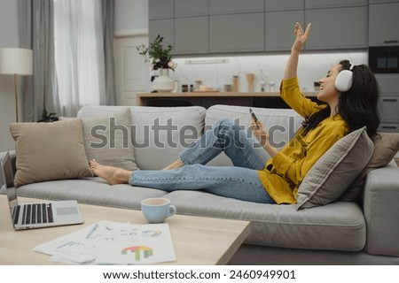 Thoughtful young woman in eyewear using computer while sitting on the sofa at home. High quality photo