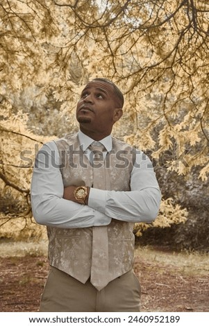 Elegantly dressed Latin American man with crossed arms and gold watch. Autumn concept