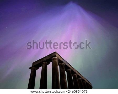 Stunning Aurora Borealis over Edinburgh's iconic National Monument on Calton Hill. Vibrant purple and pink hues dance across the night sky, illuminating the Greek-style columns.