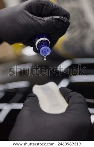 man wearing black gloves applying ceramic coating to car using sponge. Professional car detailing