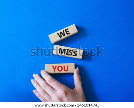 We Miss you symbol. Concept words We Miss you on wooden blocks. Beautiful blue background. Man hand. Emotion and We Miss you concept. Copy space.