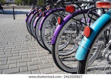 A row of bicycles wheels for rent standing in the street