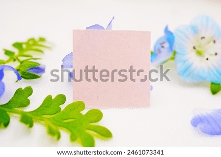 Mockup of a cute pink title card decorated with beautiful blue nemophila flowers and leaves on a white background