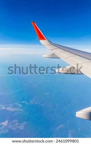 Aerial view from airplane window above green ground. View from the airplane window with beautiful clouds at sunrise. Earth and sky as seen through window of an airplane.