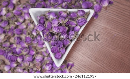 Dried damask rose buds in small bowl on wooden table