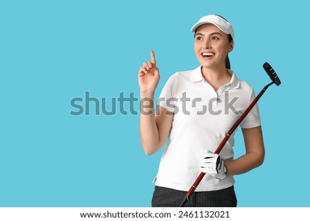 Beautiful female golfer pointing at something on blue background
