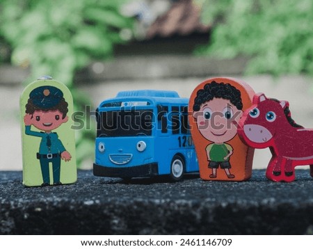 several wooden human and animal figurines on wood, and also one plastic car toy for kids