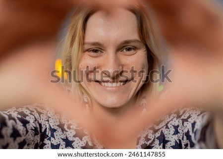 I love you. Portrait of happy Caucasian young woman at home living room couch makes symbol of love, showing heart sign to camera, express romantic feelings express sincere positive feelings. Gratitude