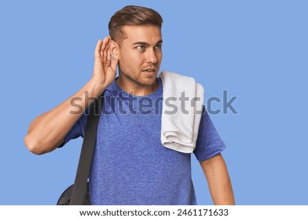 Athlete with gym bag, studio trying to listening a gossip. Royalty-Free Stock Photo #2461171633