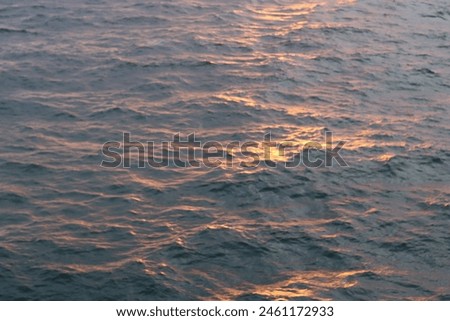 Dawn at sea, with waves tinged with golden sunlight Royalty-Free Stock Photo #2461172933