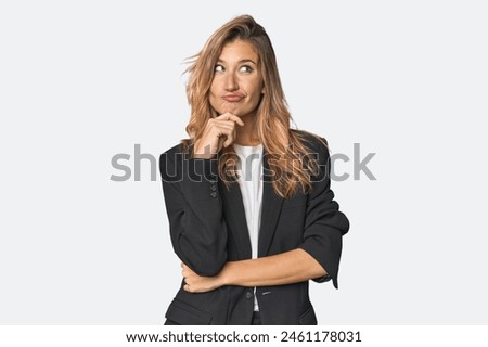Young businesswoman in a suit thinking and looking up, being reflective, contemplating, having a fantasy.