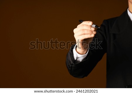 A man in a suit holds a pen