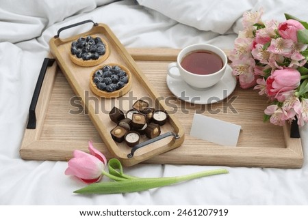Tasty breakfast served in bed. Delicious desserts, tea, flowers and blank card on tray