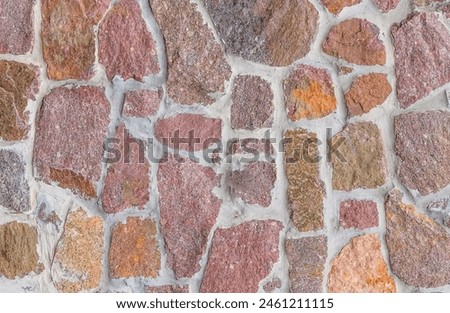 It's a close up view of colorful wall. Its photo of multicolor stonewall. It is photo of multicolored srone wall. its view of red sidewalk. It's view of mosaic stonewall