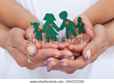 Loving family concept with adult and child hands holding paper people- shallow depth of field