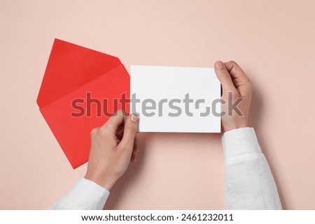Woman with blank card at beige table, top view. Space for text