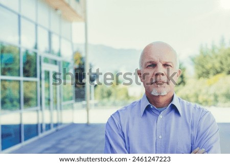 Distinguished man in professional attire stands confidently by a modern architectural backdrop, symbolizing stability and experience Royalty-Free Stock Photo #2461247223