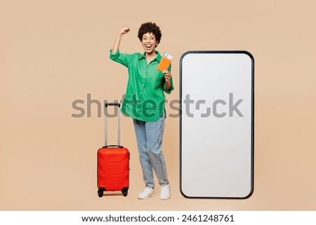 Full body traveler woman wear green casual clothes big huge blank screen mobile cell phone hold passport ticket bag isolated on plain beige background. Tourist travel in free time. Air flight concept