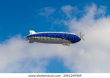 An airship against a background of blue sky and white clouds Royalty-Free Stock Photo #2461249569