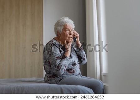 Senior woman making phone call, spending time alone in her apartment. Concept of loneliness and dependence of retired people. Royalty-Free Stock Photo #2461284659