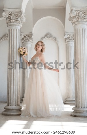 Sweet tender girl bride with a wedding bouquet in the main hall with columns.