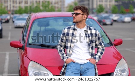 Handsome young man in eyeglasses posing near his car outdoors and showing thumb up. Trip, transportation, vacation, lifestyle concept. Slow motion