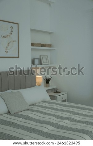 Large bed, pictures and shelves with accessories in stylish bedroom