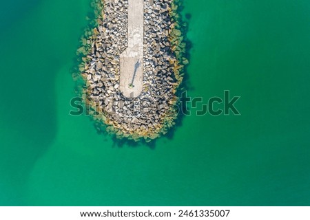 breakwater built with stone blocks in a sea of turquoise waters. Top view with drone
