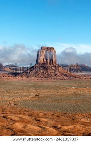 Low rainclouds hug a butte in Monument Valley's Navajo Tribal Park as rain hydrates the dry desert terrain. Royalty-Free Stock Photo #2461339837