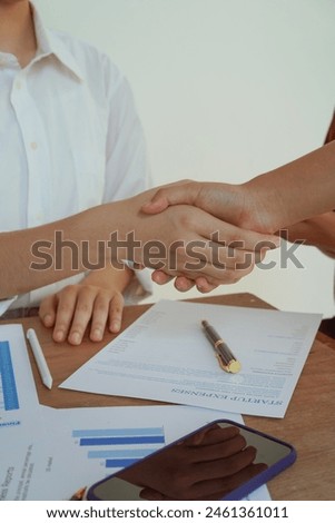 A group of professional businesswomen engaged in a collaborative meeting in a modern office setting. Concentrated and smiling, they discuss ideas and plans for successful teamwork shaking hands