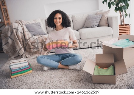 Photo of attractive charming cute girl wearing trendy clothes sitting floor putting clothes preparing relocation indoors