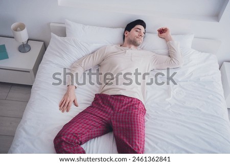 Photo of young attractive man peaceful sleeping lying in soft comfy bed white room interior inside