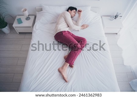 Photo of tired attractive man peaceful sleeping after work day lying in soft comfy bed white room interior inside