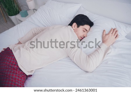 Photo of handsome attractive sleepy man peaceful relax lying in soft comfy bed white room interior inside