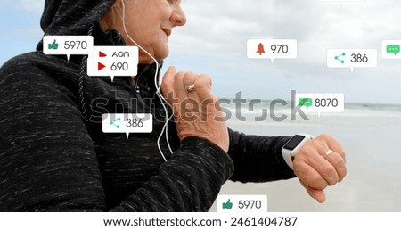 Image of notification bars over senior caucasian woman with headphone using smartwatch at beach. Digital composite, multiple exposure, social media reminder, retirement and technology concept.