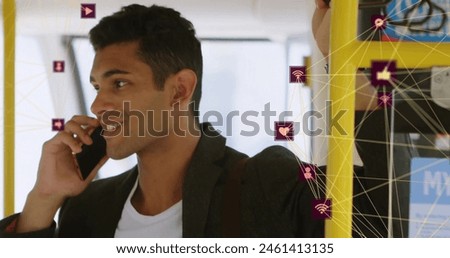 Image of connected icons globes over biracial man standing in bus and talking on smartphone. Digital composite, multiple exposure, communication, globalization, transportation, technology.