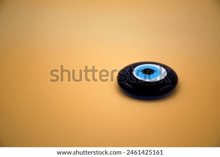 Turkish Traditional Believed by Some People About for Blue Bead Worn Against Evil Eye Talisman Amulet Made of Navy Glass isolated on yellow background Royalty-Free Stock Photo #2461425161