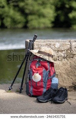 Backpack and other gear of a pilgrim to Santiago de Compostela leaning against a stone wall. Camino de Santiago concept. Copy space