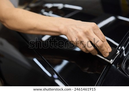 man wearing black gloves applying ceramic coating to car using sponge. Professional car detailing