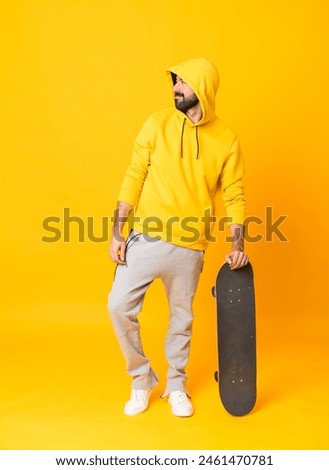 Full-length shot of a skater man over isolated yellow background