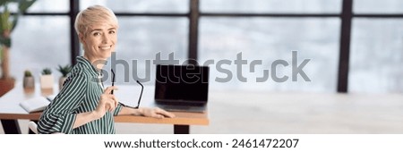 Happy Middle Aged Businesswoman Sitting At Laptop At Workdesk Smiling To Camera In Modern Office. Panorama With Copy Space