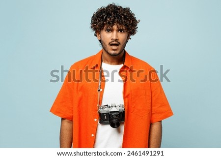 Traveler frowning sad mad Indian man wear orange casual clothes look camera isolated on plain blue background. Tourist travel abroad in free spare time rest getaway. Air flight trip journey concept Royalty-Free Stock Photo #2461491291